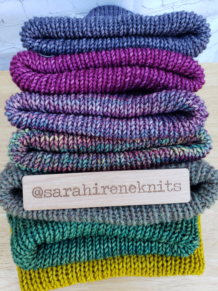 Beautiful stack of double brim beanies in various colors with @sarahireneknits tag.