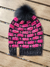 Load image into Gallery viewer, Black and hot pink checkered pattern beanie with a black faux fur pom on top.
