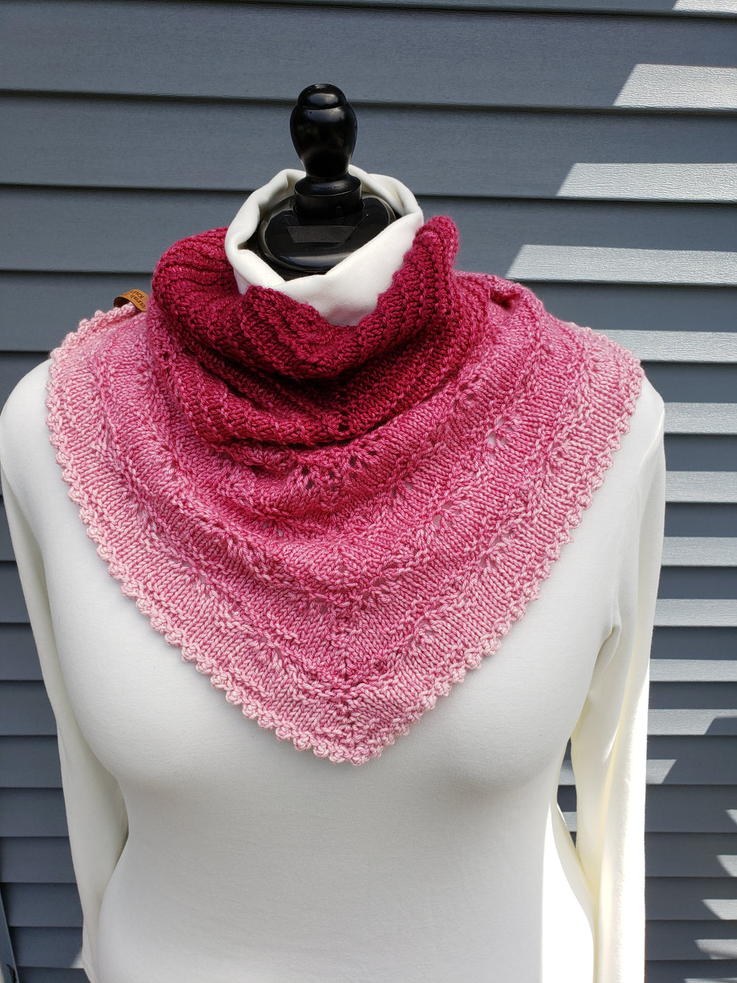 Lacy cowl from neck to bust in gradient yarn -- red at neck to light pink at bust.
