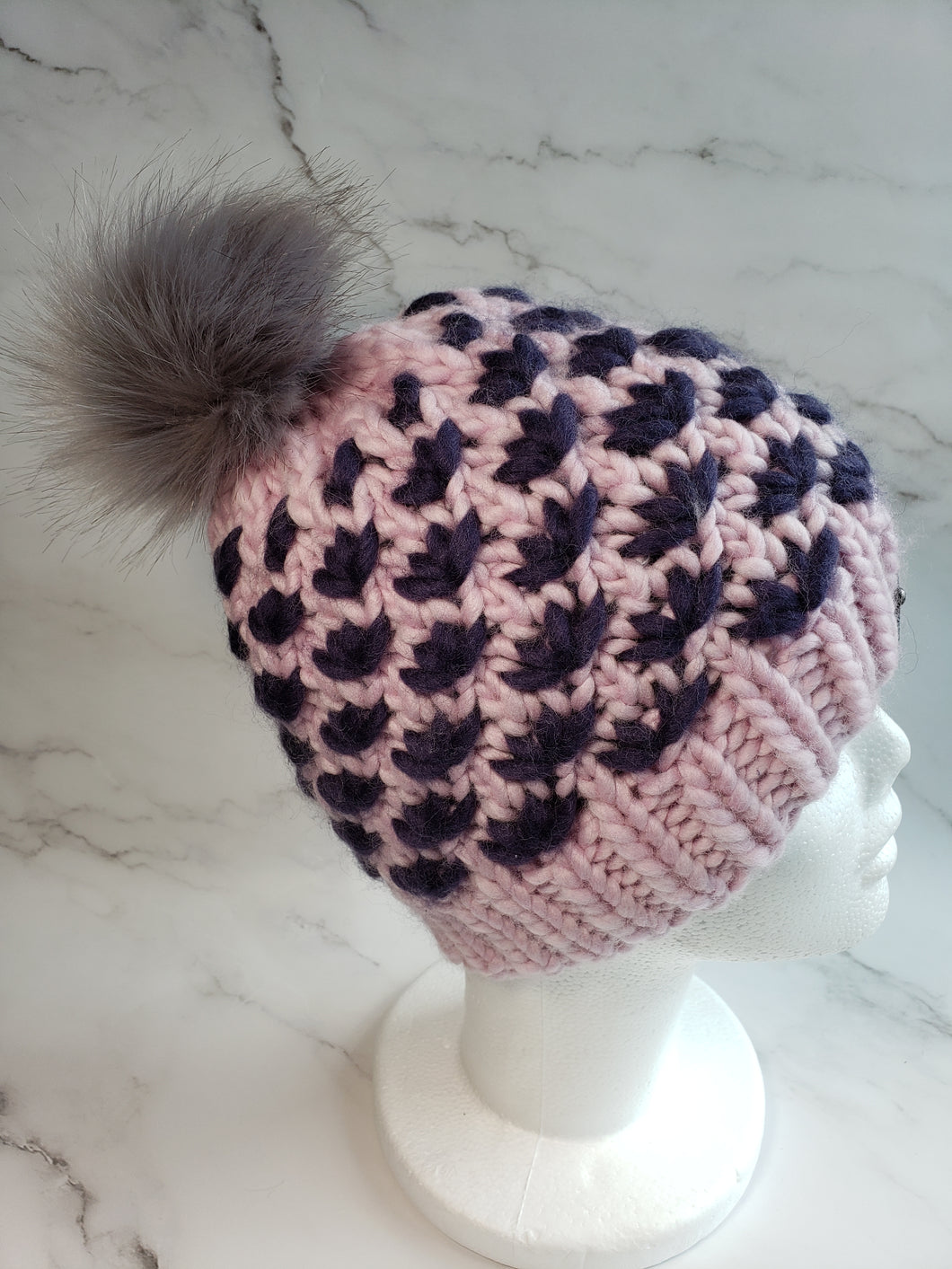 Lotus Flower beanie in pink with dark purple flowers. Grey faux fur pom on top.