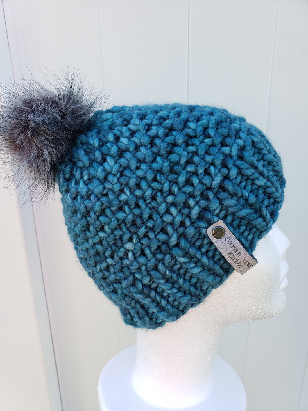 Knobby beanie in teal topped with a faux fur pom.