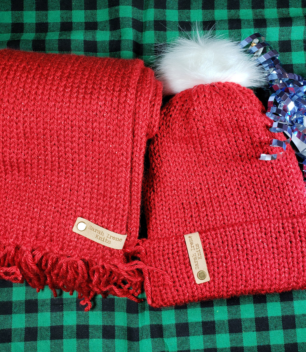 Gift set of sparkling red beanie and matching scarf. Beanie is topped with a white faux fur pom.