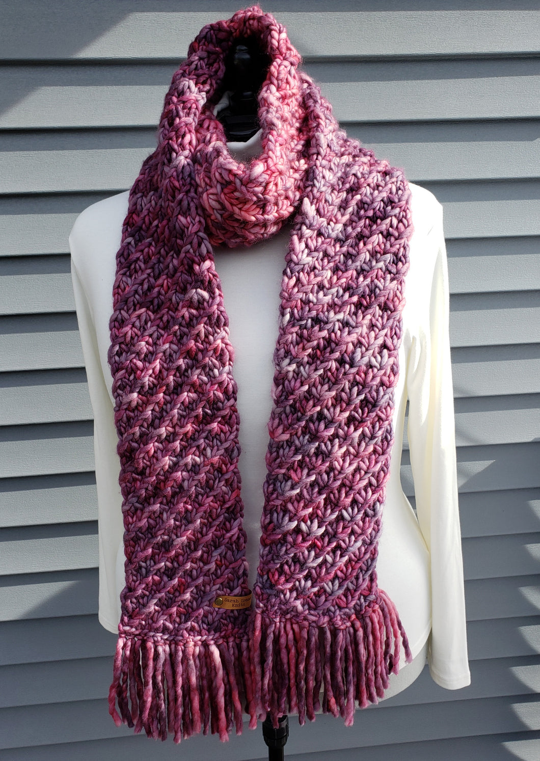 Rose pink and purple multicolor scarf with lotus pattern and fringe on a dressform model.