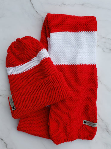 Red and white striped scarf next to a red double brim beanie with a white stripe around it. 