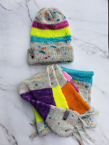 Knit scarf and hat in rainbow neon blocks of color alongside speckled blocks of color.