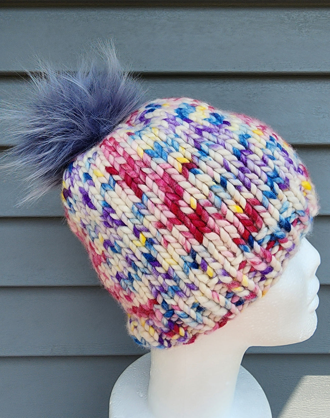 Multicolored Classic Beanie with Grey-Blue faux fur pom on top.