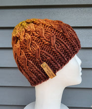 Load image into Gallery viewer, Cable effect beanie in gradient from Brown to orange to yellow-green on top.
