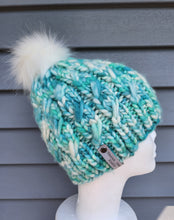 Load image into Gallery viewer, Blue, green, teal, and white speckled yarn beanie in cabled effect pattern with white faux fur pom on top.
