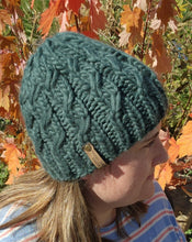 Load image into Gallery viewer, Model wearing evergreen colored braided effect beanie in alpaca fuzzy yarn. No pom.
