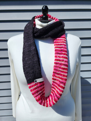 Infinity scarf with block of solid black and block of veriegated pink, red, and white yarn