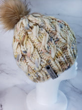 Load image into Gallery viewer, Beanie with cabling effect in a multicolor yarn with ivory, brown, blue and yellow colors topped with a faux fur pom pom
