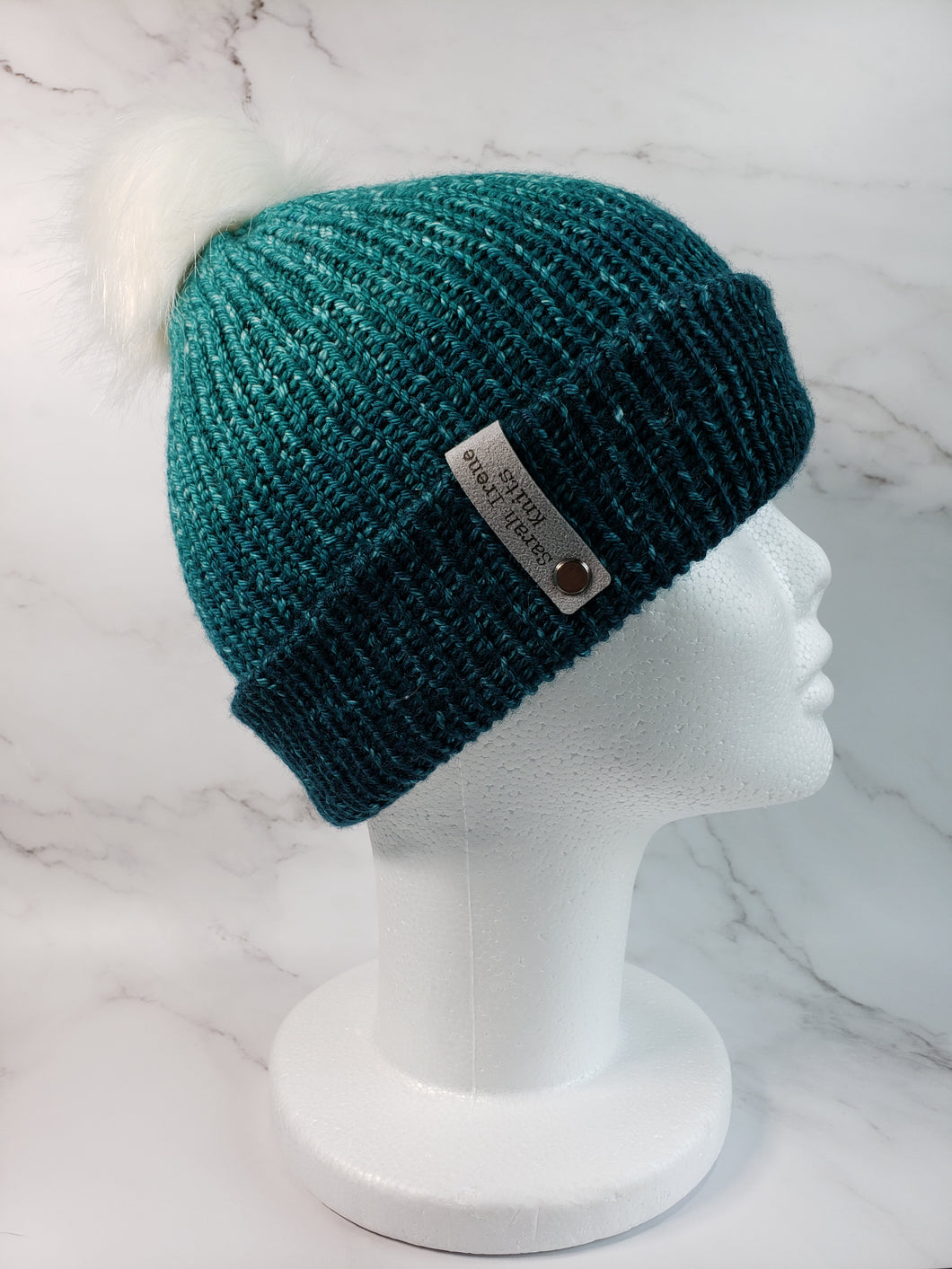 Double brim beanie in green to light green gradient. Topped with white faux fur pom.