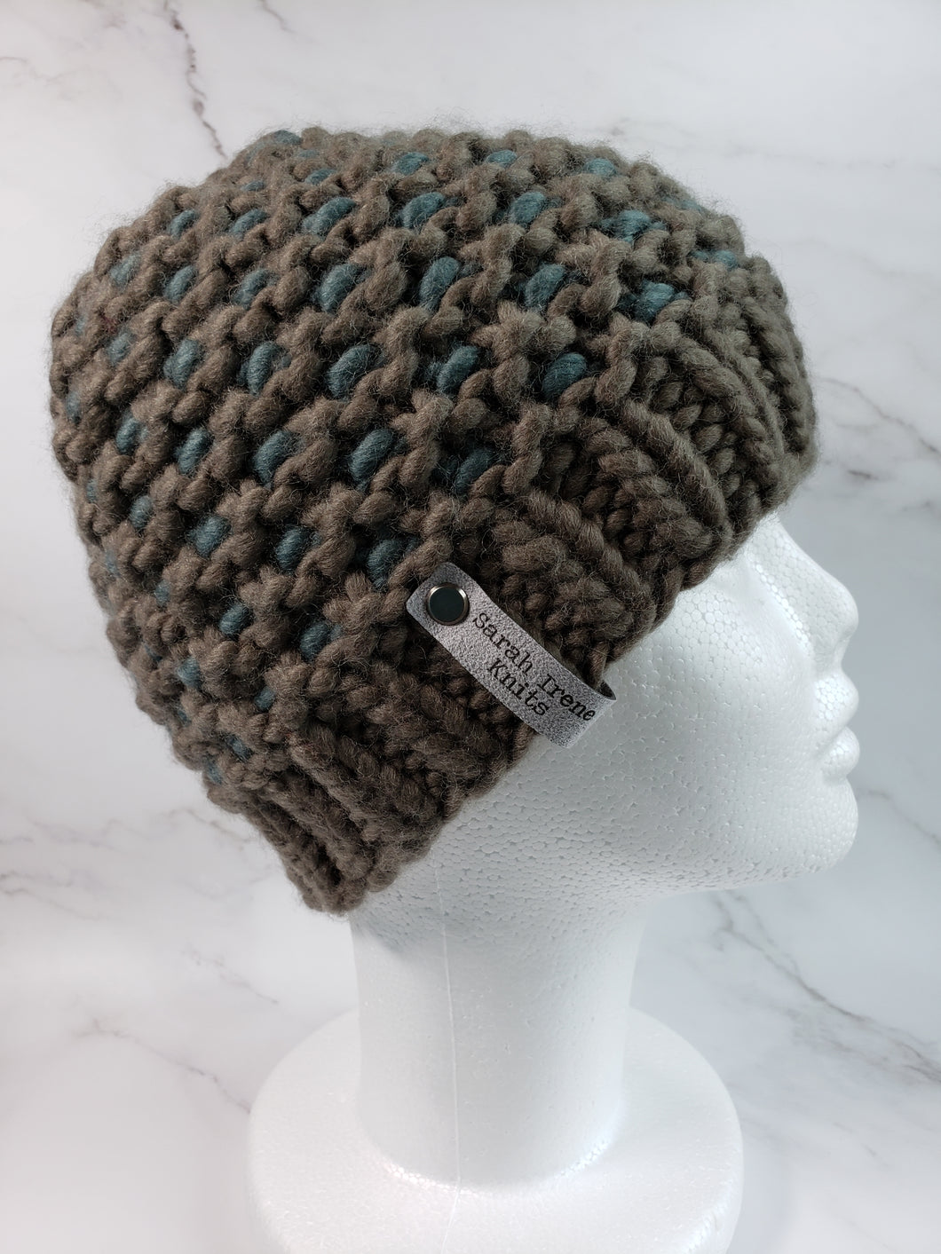 Windowpane effect beanie in a brownish grey color with teal contrast. No pom.